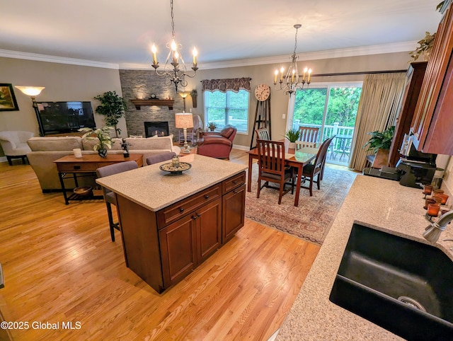 181 Fieldstone Dr, Niskayuna, NY 12304 - kitchen with a chandelier, a sink, light wood finished floors, a stone fireplace, and decorative light fixtures
