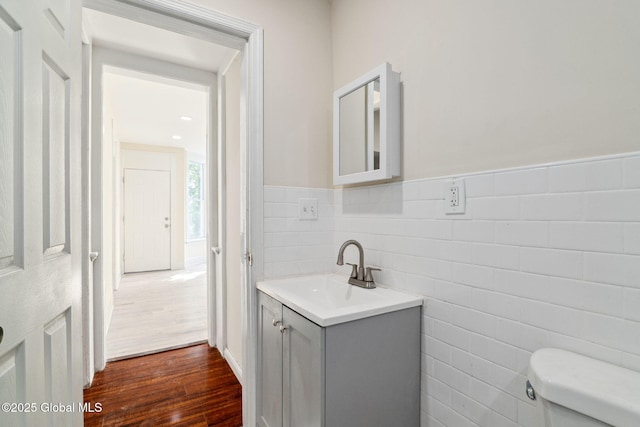 21 Kimball St, Amsterdam, NY 12010 - half bath featuring vanity, tile walls, toilet, wood finished floors, and a wainscoted wall