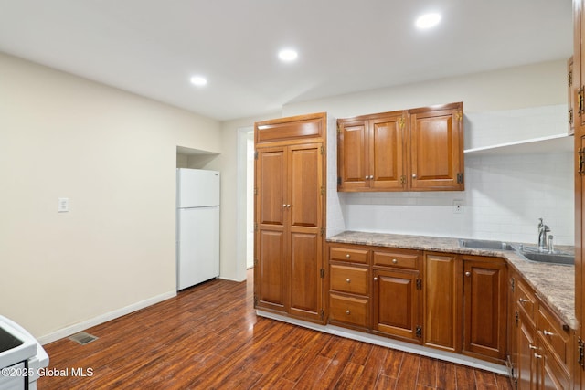 21 Kimball St, Amsterdam, NY 12010 - kitchen featuring freestanding refrigerator, a sink, backsplash, dark wood-type flooring, and brown cabinetry