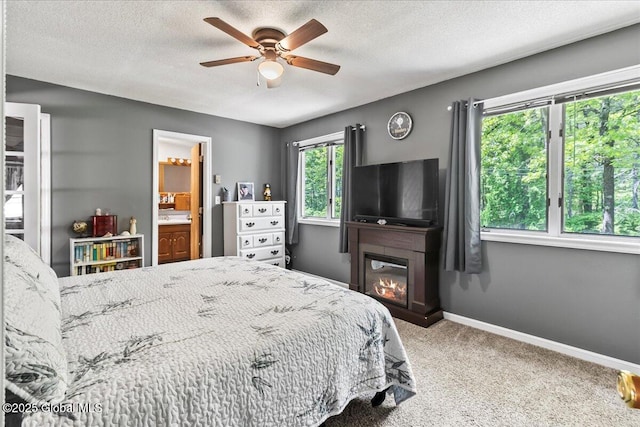 140 Redmond Rd, Moreau, NY 12831 - carpeted bedroom featuring baseboards, a textured ceiling, a glass covered fireplace, a ceiling fan, and connected bathroom
