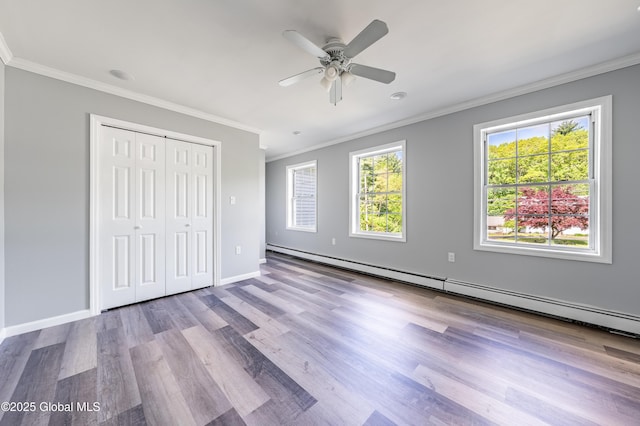 7116 Fuller Station Rd, Schenectady, NY 12303 - unfurnished bedroom with crown molding, baseboard heating, wood finished floors, baseboards, and a closet