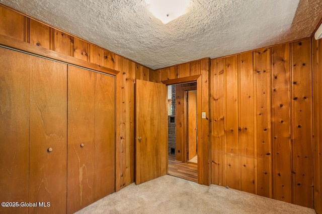 241 Kunkel Rd, Mayfield, NY 12117 - unfurnished bedroom featuring carpet, a textured ceiling, a closet, and wood walls