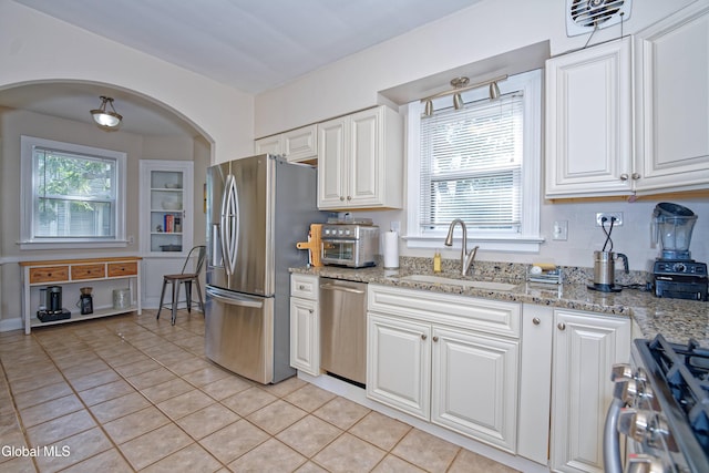 5 Kakely St, Albany, NY 12208 - kitchen with appliances with stainless steel finishes, light tile patterned floors, arched walkways, white cabinets, and light stone countertops