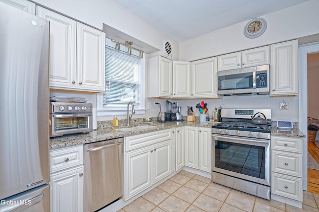5 Kakely St, Albany, NY 12208 - kitchen with appliances with stainless steel finishes, light tile patterned floors, white cabinets, and light stone counters