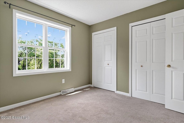 21 Fairway Dr Unit B, Mechanicville, NY 12118 - unfurnished bedroom with carpet, baseboards, multiple closets, and a textured ceiling