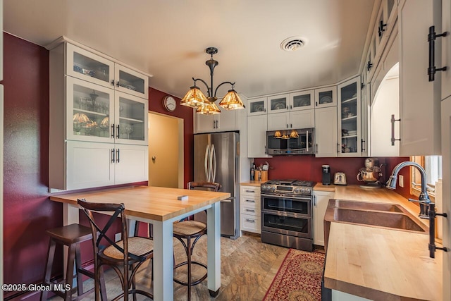 7 Western Ave, Charlton, NY 12019 - kitchen featuring stainless steel appliances, butcher block countertops, a sink, hanging light fixtures, and a chandelier