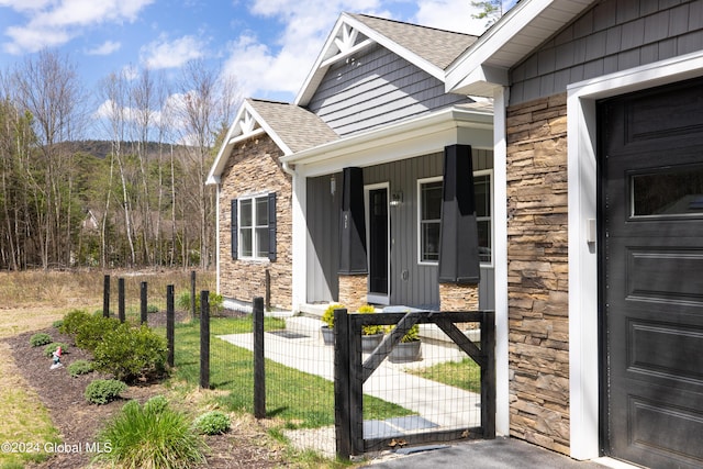 51 Rollman Cir, Hadley, NY 12835 - view of exterior entry with stone siding, roof with shingles, a gate, and a porch