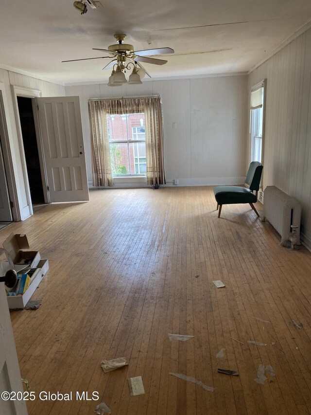 3847 Main St, Warrensburg, NY 12885 - unfurnished living room with radiator heating unit, hardwood / wood-style flooring, ceiling fan, plenty of natural light, and ornamental molding