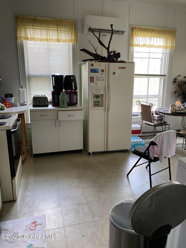 3847 Main St, Warrensburg, NY 12885 - kitchen featuring white fridge with ice dispenser, stove, an AC wall unit, light countertops, and white cabinetry