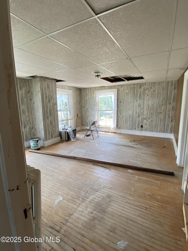 3847 Main St, Warrensburg, NY 12885 - unfurnished room with a drop ceiling, wood walls, wood-type flooring, and baseboards