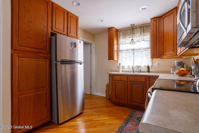 209 Whitehall Rd, Albany, NY 12209 - kitchen with appliances with stainless steel finishes, light wood finished floors, brown cabinetry, a sink, and pendant lighting