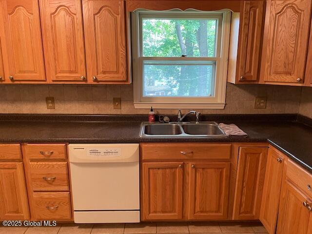 2070 Grand Blvd, Niskayuna, NY 12309 - kitchen featuring white dishwasher, a sink, dark countertops, light tile patterned floors, and brown cabinets