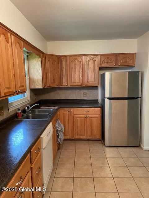 2070 Grand Blvd, Niskayuna, NY 12309 - kitchen with freestanding refrigerator, a sink, light tile patterned floors, white dishwasher, and dark countertops