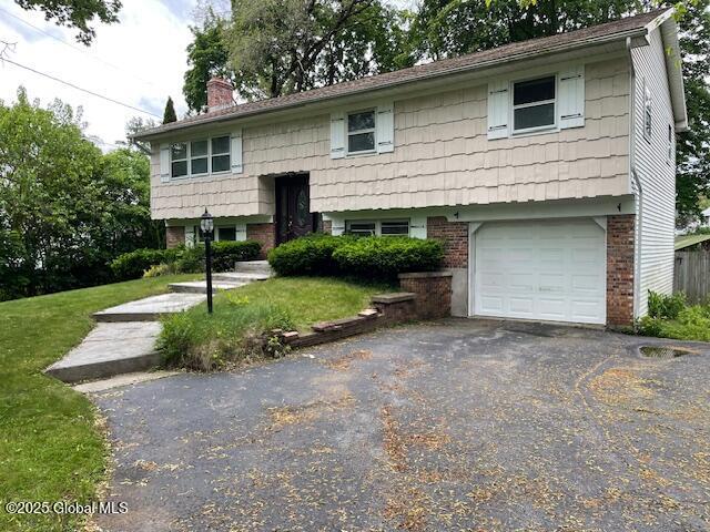 2070 Grand Blvd, Niskayuna, NY 12309 - split foyer home with a garage, a chimney, driveway, and a front lawn