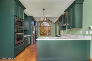 138 Lydon Ln, New Baltimore, NY 12087 - kitchen featuring appliances with stainless steel finishes, a peninsula, green cabinets, light wood-style floors, and lofted ceiling
