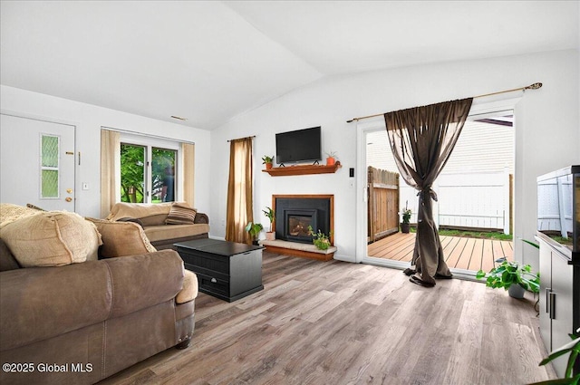 60 Tallow Wood Dr, Clifton Park, NY 12065 - living room featuring vaulted ceiling, wood finished floors, a fireplace with raised hearth, and healthy amount of natural light