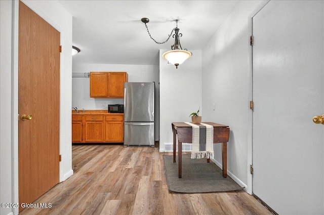 60 Tallow Wood Dr, Clifton Park, NY 12065 - kitchen featuring freestanding refrigerator, black microwave, brown cabinets, and light wood-type flooring