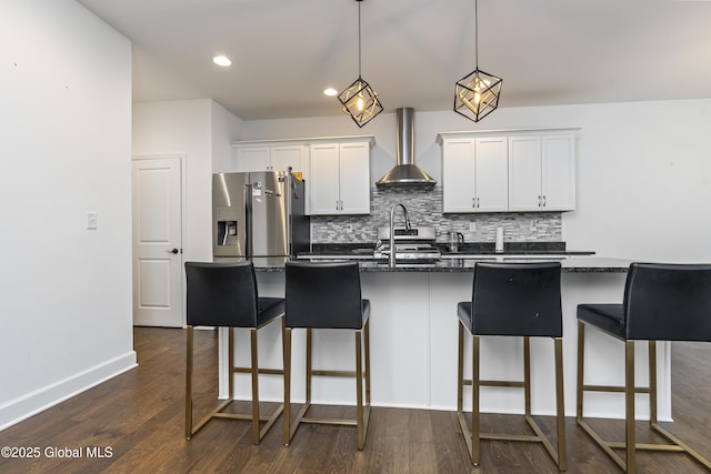 2 Hillard Ln, Colonie, NY 12110 - kitchen featuring wall chimney range hood, appliances with stainless steel finishes, a breakfast bar area, a kitchen island with sink, and dark countertops