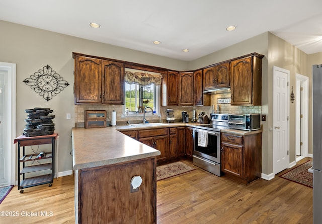 3119 State Route 150, Schodack, NY 12063 - kitchen featuring electric range, a sink, a peninsula, under cabinet range hood, and light wood-type flooring