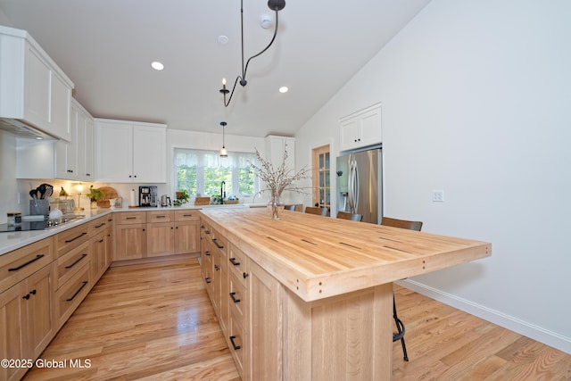 17 Ringwald Rd, Coeymans, NY 12046 - kitchen with stainless steel refrigerator with ice dispenser, butcher block counters, light wood-style floors, a breakfast bar area, and light brown cabinets