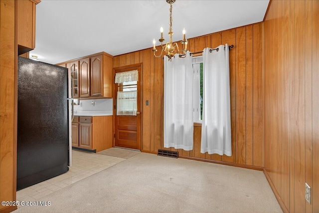 149 Wilton Rd, Greenfield, NY 12833 - kitchen featuring freestanding refrigerator, brown cabinetry, plenty of natural light, wood walls, and a chandelier