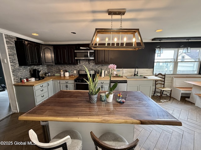 243 N Perry St, Johnstown, NY 12095 - kitchen featuring stainless steel appliances, a sink, decorative backsplash, decorative light fixtures, and wood finished floors