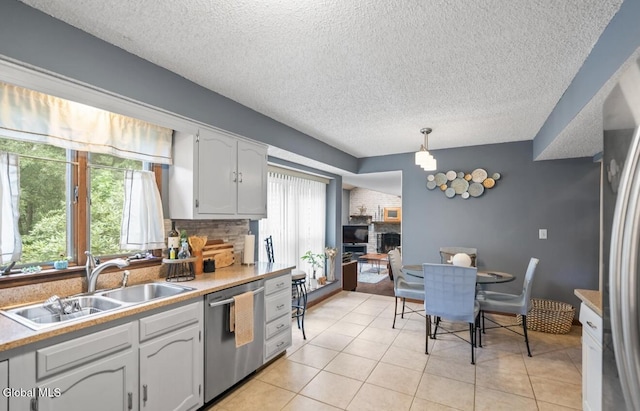 7 Hawthorn Cir, Albany, NY 12203 - kitchen with dishwasher, a textured ceiling, light countertops, decorative light fixtures, and a brick fireplace