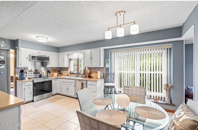 7 Hawthorn Cir, Albany, NY 12203 - kitchen featuring appliances with stainless steel finishes, light countertops, backsplash, hanging light fixtures, and a textured ceiling