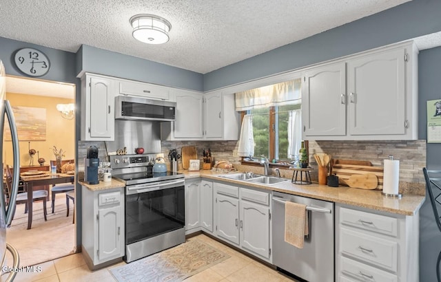 7 Hawthorn Cir, Albany, NY 12203 - kitchen with stainless steel appliances, a textured ceiling, light tile patterned floors, backsplash, and white cabinetry