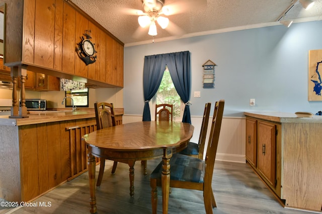 202 Lakeland Rd, Edinburg, NY 12835 - dining area with a textured ceiling, a ceiling fan, wood finished floors, a wainscoted wall, and crown molding