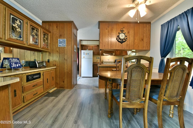 202 Lakeland Rd, Edinburg, NY 12835 - dining room with ceiling fan, a textured ceiling, crown molding, light wood-style floors, and wood walls