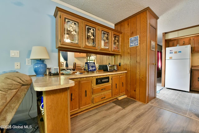 202 Lakeland Rd, Edinburg, NY 12835 - kitchen with freestanding refrigerator, crown molding, a peninsula, brown cabinetry, and glass insert cabinets