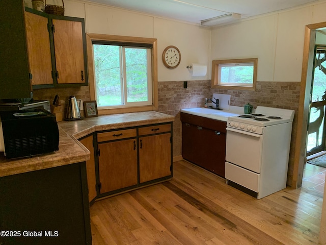 847 Lake Ave, Lake Luzerne, NY 12846 - kitchen with white range with electric stovetop, light wood-type flooring, tasteful backsplash, and brown cabinetry