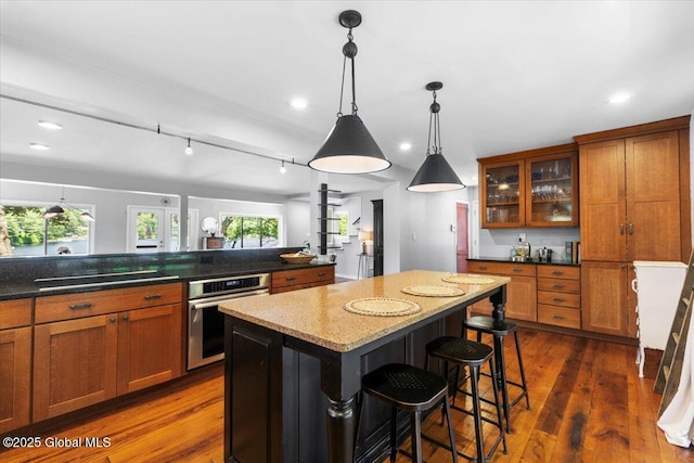 162 Methodist Farm Rd, Sand Lake, NY 12018 - kitchen with stainless steel oven, black electric cooktop, brown cabinets, a kitchen breakfast bar, and a kitchen island