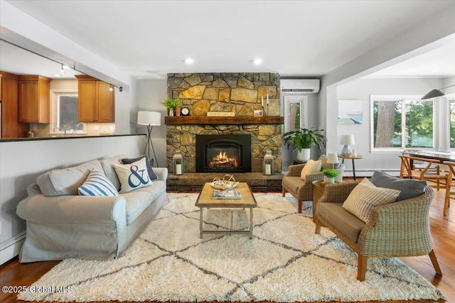 162 Methodist Farm Rd, Sand Lake, NY 12018 - living area with an AC wall unit, wood finished floors, a stone fireplace, recessed lighting, and baseboard heating