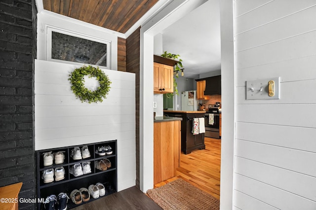 784 Ny Highway 351, Poestenkill, NY 12140 - kitchen with stainless steel electric stove, light wood-style floors, ventilation hood, freestanding refrigerator, and wooden walls