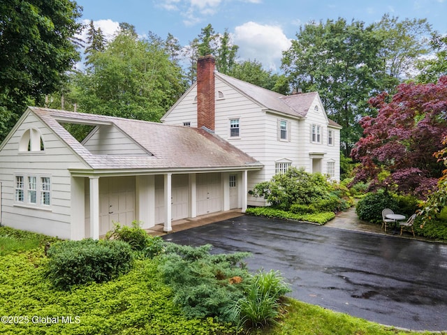 20 Darroch Rd, Bethlehem, NY 12054 - rear view of house featuring asphalt driveway, a chimney, a shingled roof, and an attached garage