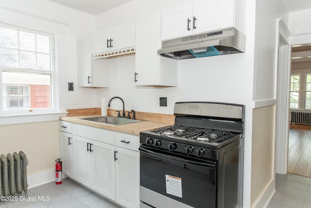 210 N Ballston Ave, Scotia, NY 12302 - kitchen with gas stove, under cabinet range hood, radiator heating unit, a sink, and baseboards