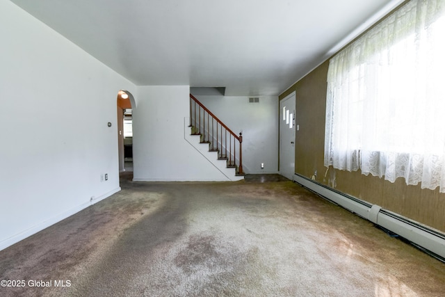 102 Willow St, Guilderland, NY 12084 - unfurnished living room featuring baseboard heating, stairway, arched walkways, and carpet floors