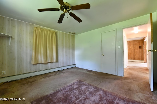 102 Willow St, Guilderland, NY 12084 - carpeted empty room featuring baseboard heating, wood walls, and ceiling fan