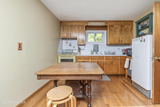 19 Knowles Rd, Rensselaerville, NY 12469 - kitchen featuring freestanding refrigerator, stainless steel stove, light wood-type flooring, brown cabinets, and light countertops