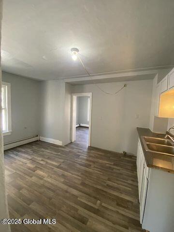 225 Main St, Fort Plain, NY 13339 - kitchen with a sink, a baseboard radiator, dark wood-style floors, dark countertops, and white cabinetry