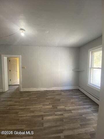 225 Main St, Fort Plain, NY 13339 - empty room with dark wood-style flooring, baseboards, and a baseboard heating unit