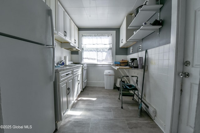 140 3rd St, Troy, NY 12180 - kitchen featuring white appliances, under cabinet range hood, white cabinetry, tile walls, and wainscoting