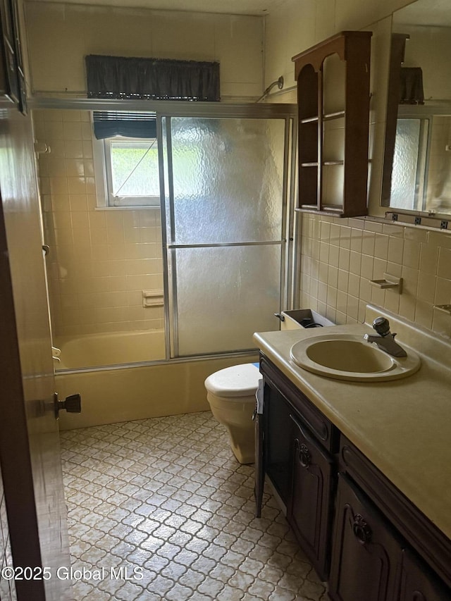 63 Ormond St, Albany, NY 12203 - full bathroom featuring vanity, toilet, bath / shower combo with glass door, tile walls, and tasteful backsplash