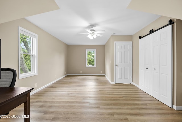 7 Camp Ter, Guilderland, NY 12203 - unfurnished bedroom featuring multiple windows, a desk, light wood-style flooring, and a barn door