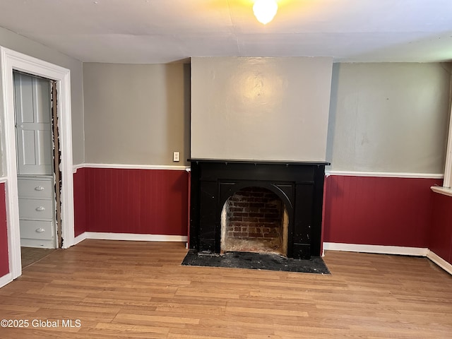 369 Madison Ave, Albany, NY 12210 - unfurnished living room with a wainscoted wall, a fireplace with flush hearth, wood finished floors, and baseboards