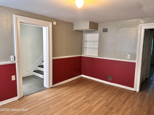 369 Madison Ave, Albany, NY 12210 - spare room with wood finished floors, stairs, a wainscoted wall, and a smoke detector