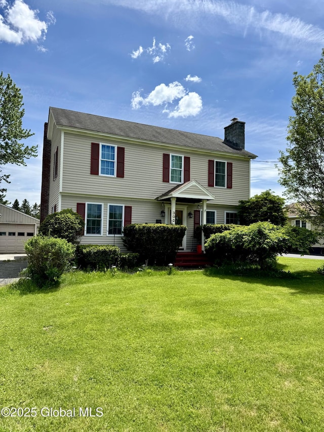 302 Pennsylvania Ave, Johnstown, NY 12095 - colonial house featuring a chimney, a front lawn, an outdoor structure, and a garage