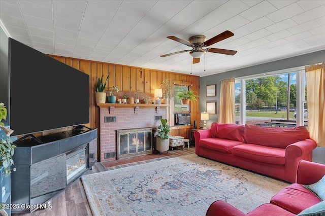3287 Ny Highway 43, Sand Lake, NY 12018 - living area featuring wood walls, a ceiling fan, wood finished floors, and a brick fireplace